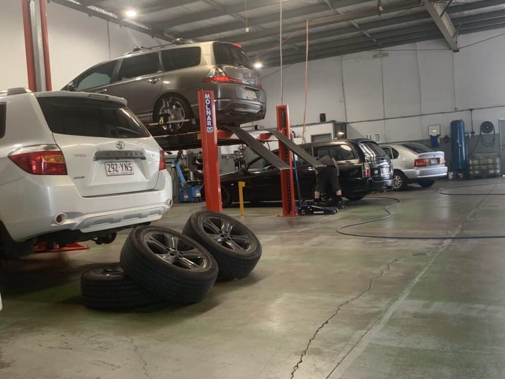 multiple cars in a mechanics garage being worked on.