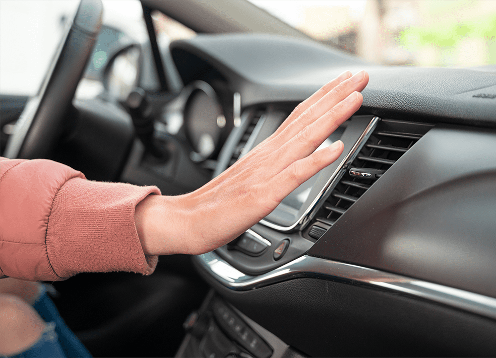 A woman's hand checking if the air-conditioning is working in her car
