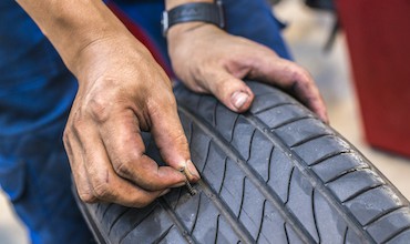 closeup of nail puncturing tire.