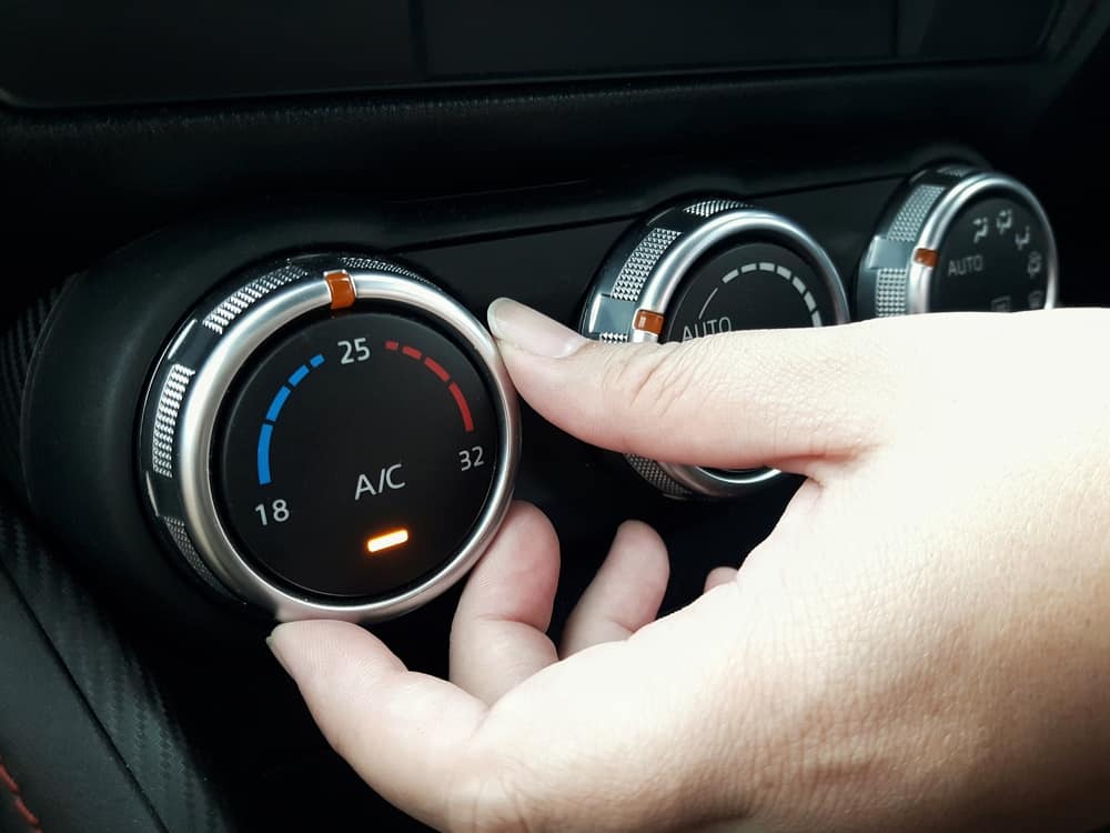 A woman's hand adjusting the air-conditioning temperature in her car